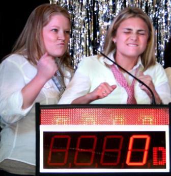 Two girls are standing at a podium and one is holding her fist up.