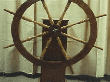 A large wooden wheel sitting on top of a floor.