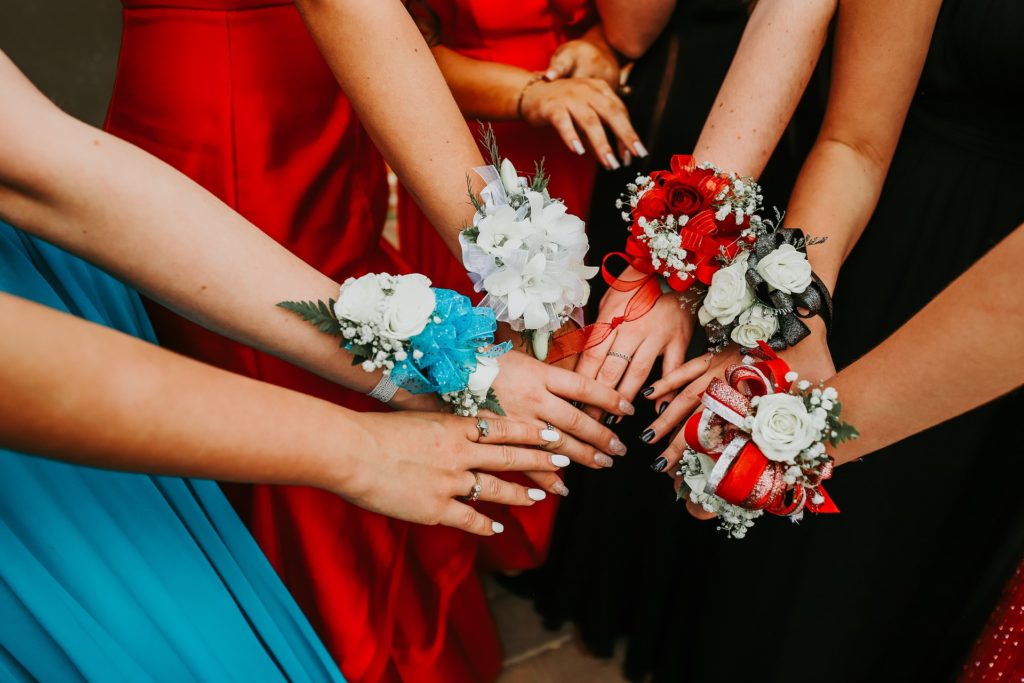 A group of people holding hands wearing corsages.
